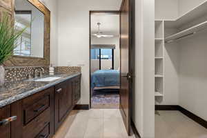 Ensuite bathroom with vanity, a ceiling fan, backsplash, and light tile patterned floors