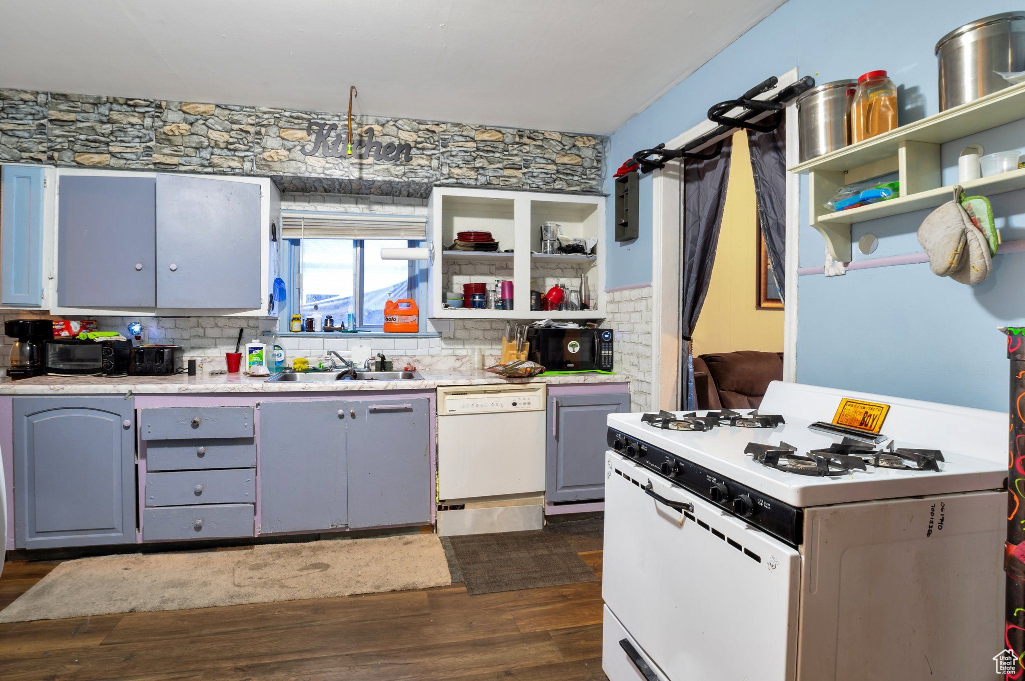 Kitchen featuring white appliances, open shelves, dark wood finished floors, and decorative backsplash