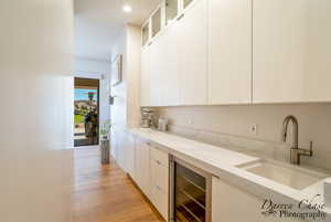 Bar with modern cabinets, glass fronted cabinets, wine cooler, white cabinetry, and recessed lighting