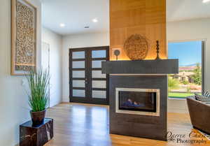 Entrance foyer featuring light wood-type flooring, recessed lighting, a glass covered fireplace, and french doors