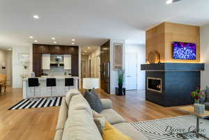 Living area with light wood finished floors, a large fireplace, and recessed lighting