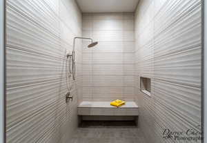 Bathroom featuring tiled shower and tile walls