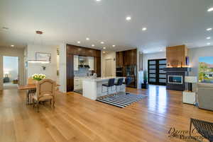 Living room with recessed lighting, a fireplace, and light wood finished floors
