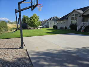 View of basketball court featuring a lawn and a residential view