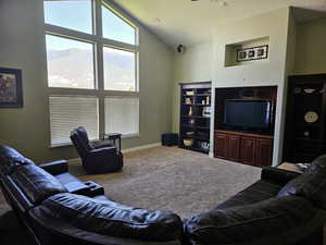 Carpeted living area featuring baseboards and lofted ceiling