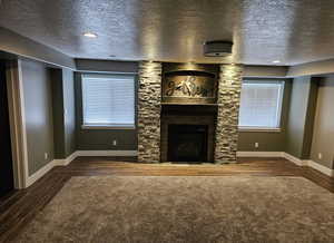 Unfurnished living room featuring a textured ceiling, dark wood-style floors, and a fireplace