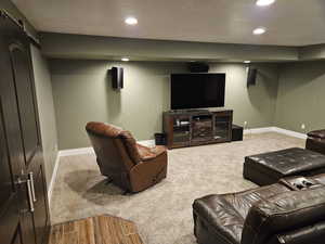 Cinema room featuring recessed lighting, a barn door, light wood-style flooring, and light colored carpet