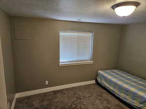 Bedroom with dark carpet and a textured ceiling