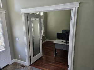 Home office featuring dark wood-style flooring and baseboards