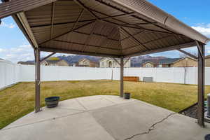 Fenced backyard featuring a patio, a residential view, and a gazebo
