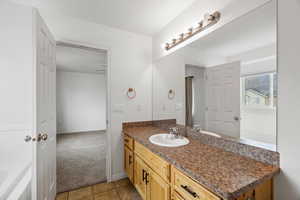 Bathroom featuring light carpet, vanity, light tile patterned floors, and a bath