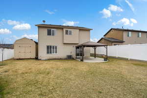 Rear view of property featuring a patio area, a storage shed, a gazebo, and a fenced backyard