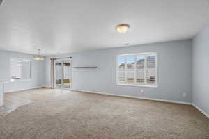 Unfurnished room featuring light carpet and suspended lighting