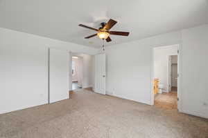 Unfurnished bedroom with light carpet, a ceiling fan, and ensuite bath