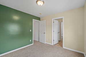 Unfurnished bedroom with light carpet and baseboards