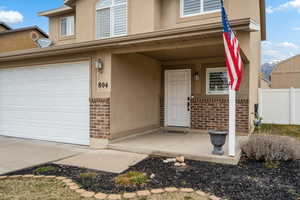 View of front of house featuring covered porch, brick siding, stucco siding, and a garage