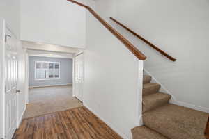 Stairway with a high ceiling, arched walkways, wood finished floors, and carpet