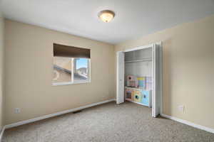 Unfurnished bedroom with light carpet and a closet