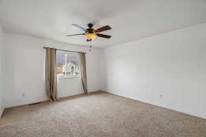 Carpeted spare room with a ceiling fan and baseboards