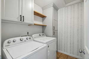 Laundry area with cabinet space, dark tile patterned floors, and separate washer and dryer