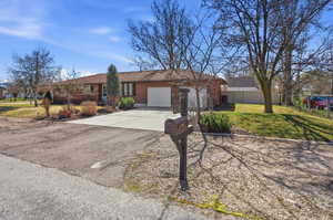 Ranch-style house featuring concrete driveway, an attached garage, and brick siding