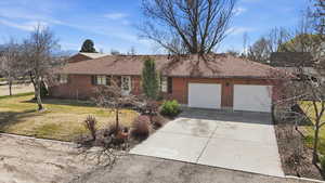 Ranch-style home featuring driveway, a front yard, a garage, brick siding, and a shingled roof