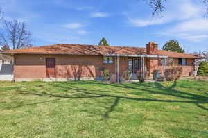 Back of property with brick siding, a yard, a chimney, and a patio area
