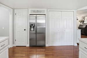 Kitchen with white cabinets, stainless steel refrigerator with ice dispenser, light countertops, and dark wood finished floors