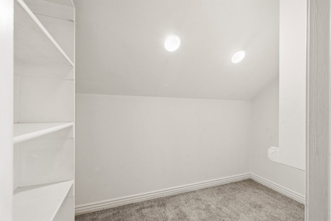 Bonus room with light colored carpet and vaulted ceiling