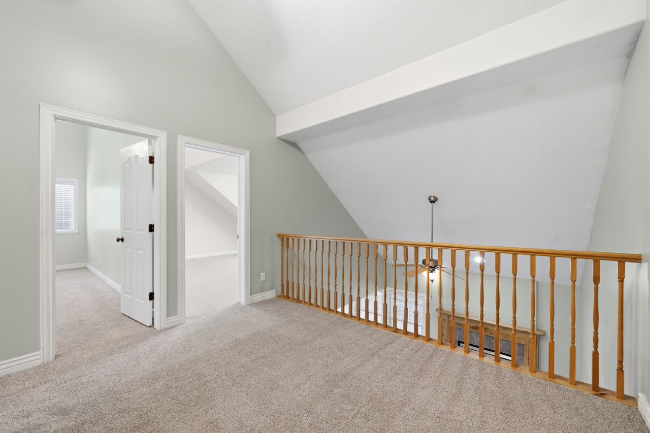 Hallway featuring vaulted ceiling and light colored carpet