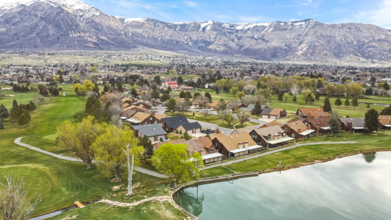Aerial view of residential area featuring a golf course and a water and mountain view