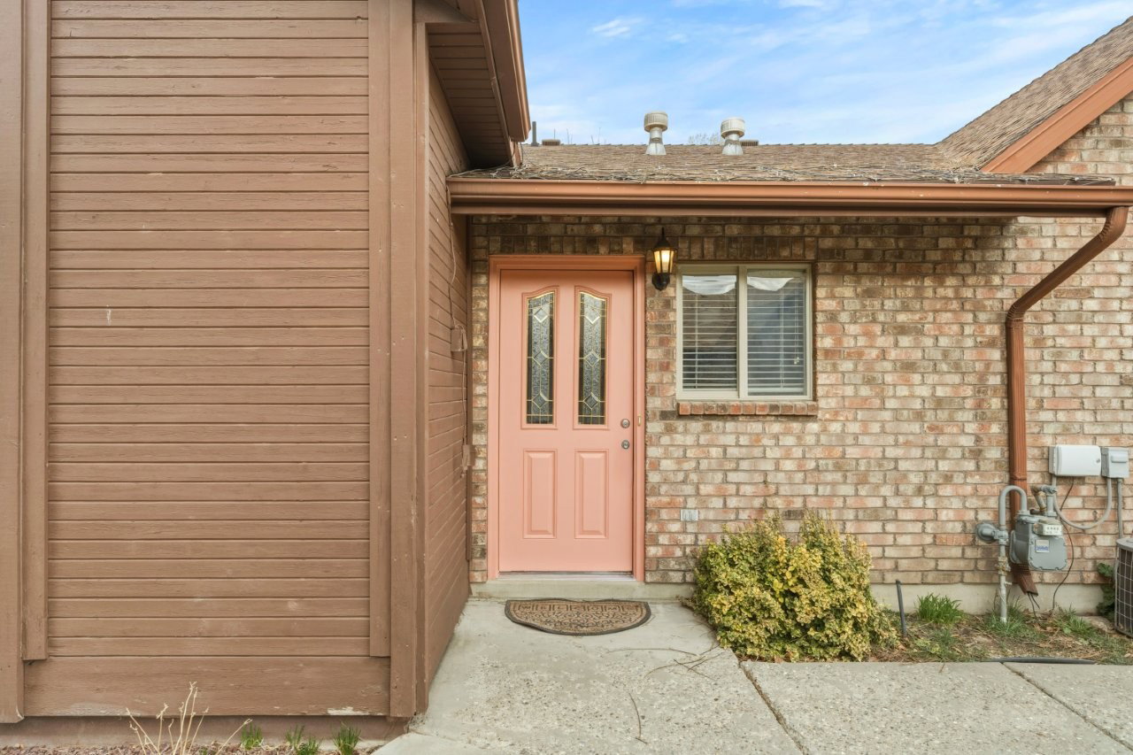 Doorway to property with brick siding and roof with shingles