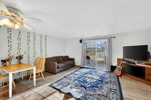 Living room with light wood-style floors, a textured ceiling, and a ceiling fan