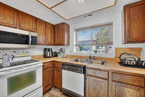 Kitchen featuring white appliances, light countertops, and wood finish cabinetry