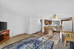 Kitchen with wood finish cabinetry, light countertops, ceiling fan, white appliances, and light wood-type flooring