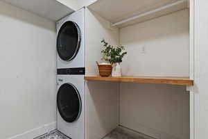 Laundry room featuring stacked washer / drying machine and concrete flooring
