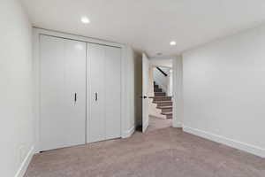 Unfurnished bedroom with a closet, light carpet, and recessed lighting