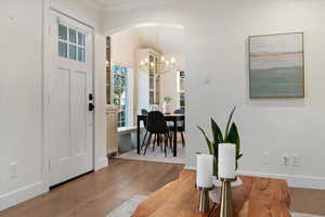Foyer entrance with wood finished floors, arched walkways, and a chandelier