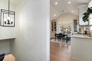 Hallway featuring a chandelier, light wood-type flooring, and vaulted ceiling