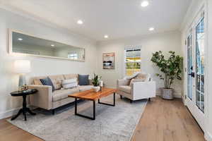 Living room with recessed lighting, light wood-style flooring, ornamental molding, and french doors