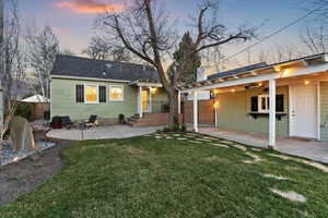 Rear view of property featuring a patio, a shingled roof, and a chimney
