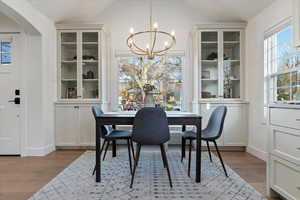 Dining space featuring healthy amount of natural light, vaulted ceiling, suspended lighting, and light wood-type flooring