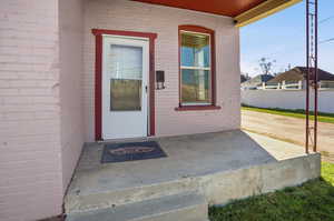 Property entrance featuring covered porch and brick siding