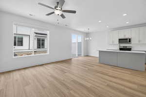 Kitchen with ceiling fan, stainless steel appliances, light wood-style flooring, a chandelier, and open floor plan