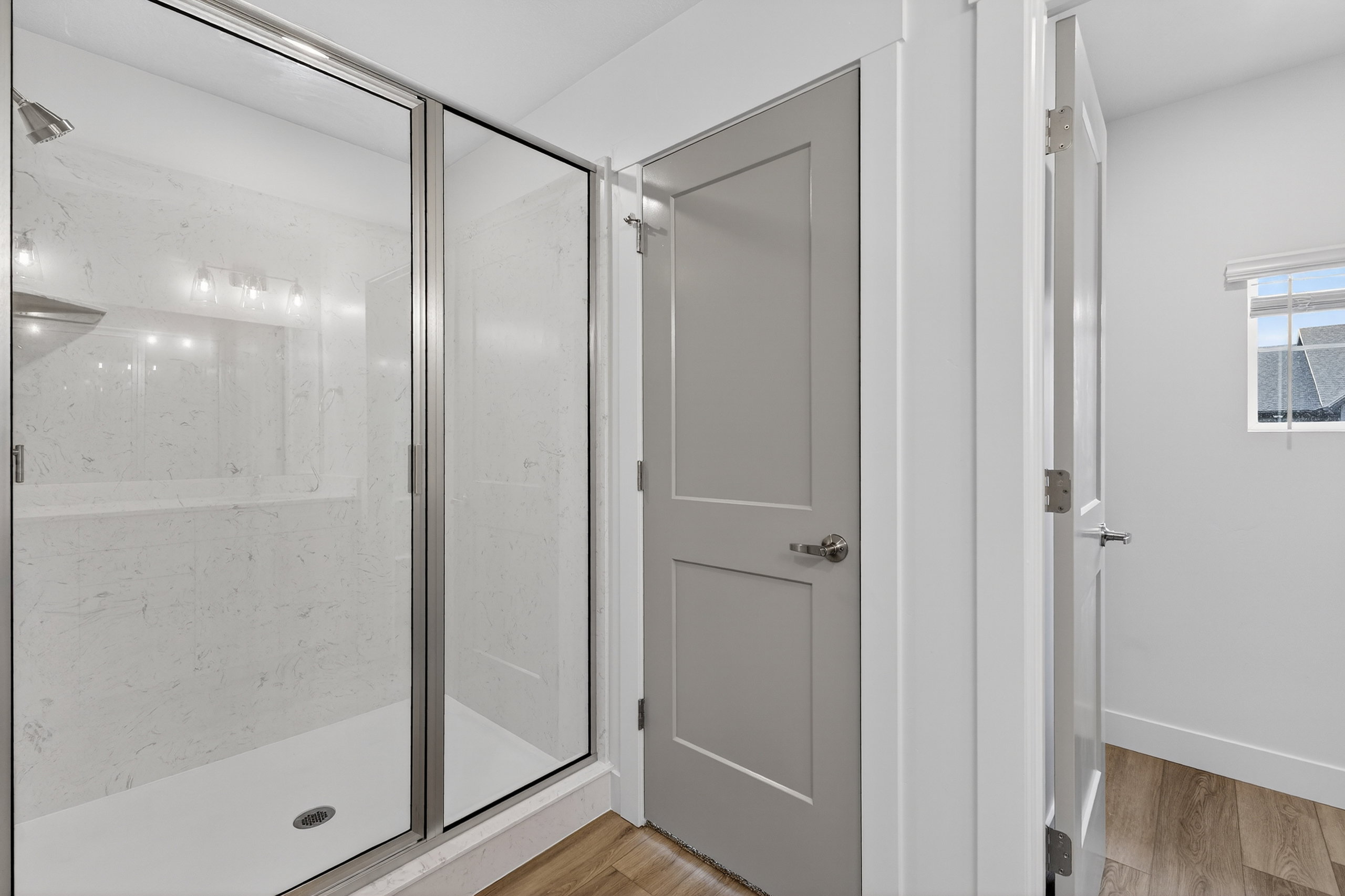 Bathroom featuring a marble finish shower and light wood-style floors