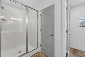 Bathroom featuring a marble finish shower and light wood-style floors