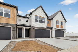 Modern home with brick siding, an attached garage, and concrete driveway