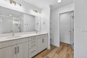 Bathroom featuring a stall shower, recessed lighting, double vanity, and light wood-style floors