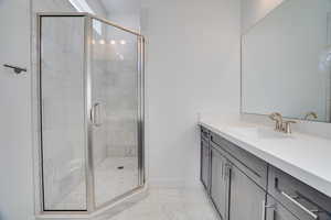 Bathroom with vanity, a shower stall, and light marble finish floors