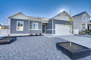 View of front of home with board and batten siding, driveway, an attached garage, and a shingled roof